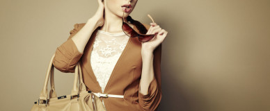 Девушка в белом платье из кружева и коричневом трикотажном жакете с сумкой и очками